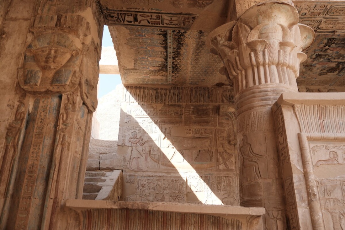 Sunlight cutting through the carved ceiling of an Egyptian temple