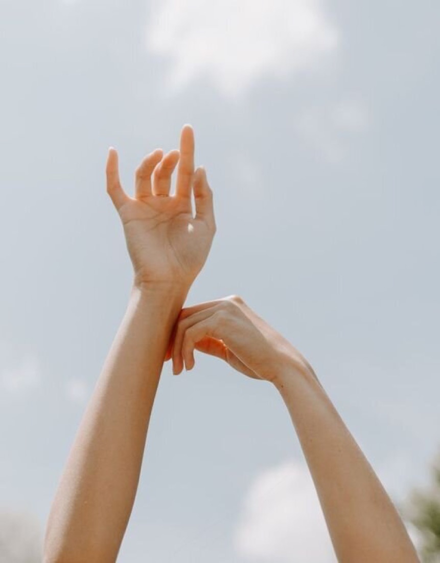 Arms raised toward the sky, fingertips reaching